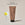 A tube of ACURE Brightening Body Scrub against a neutral background. next to a circle displaying old packaging and text calling out: New look , same proven formula